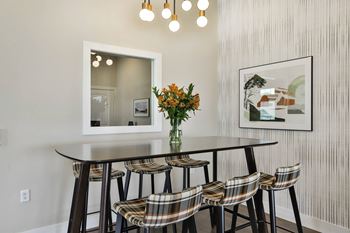 A dining room with a table and chairs and a mirror